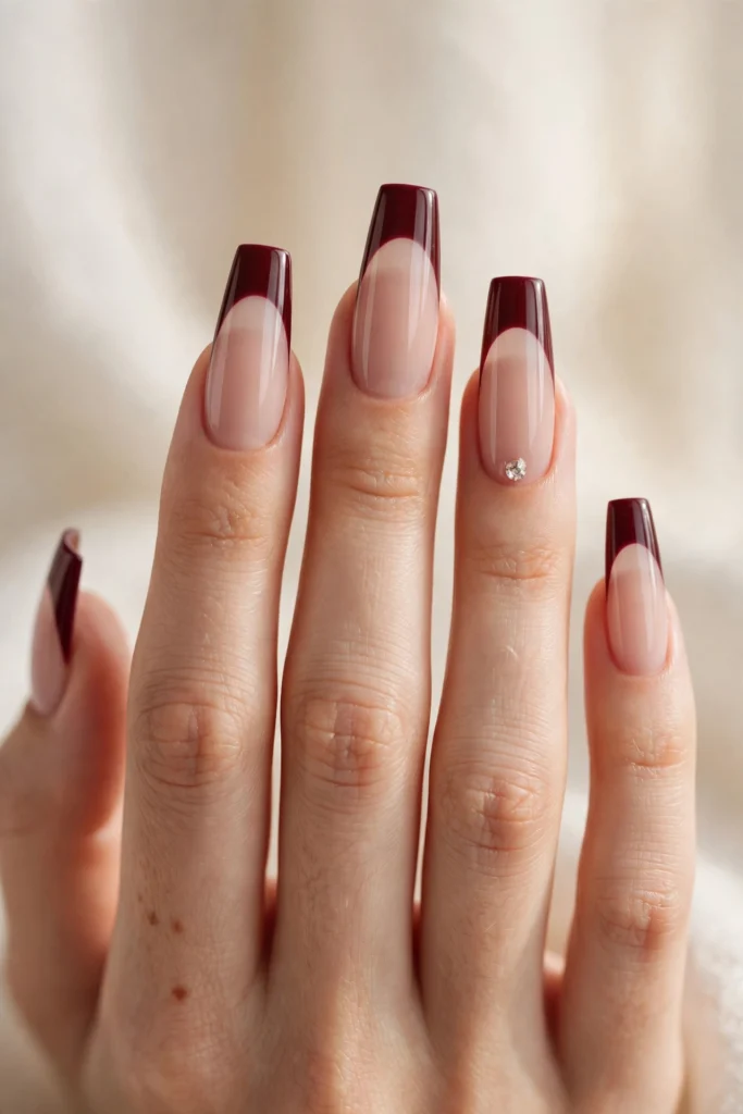 Long coffin nails with glossy wine-burgundy French tips and a single crystal rhinestone accent.