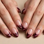 Burgundy velvet cat eye French tip nails on almond-shaped nails
