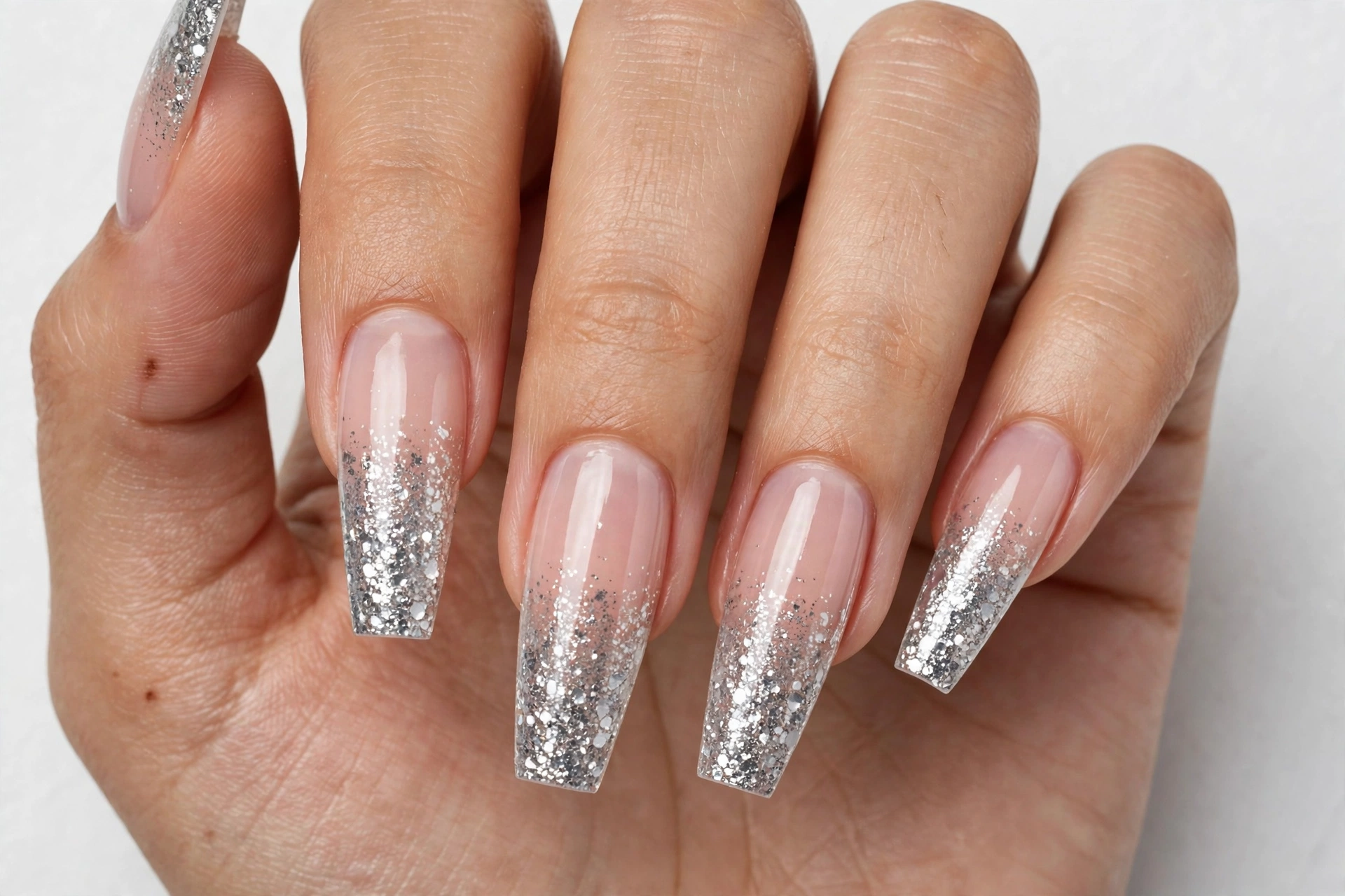 Glitter gradient coffin French tip nails with silver glitter blending from the tips into a sheer base, shown on long coffin nails.