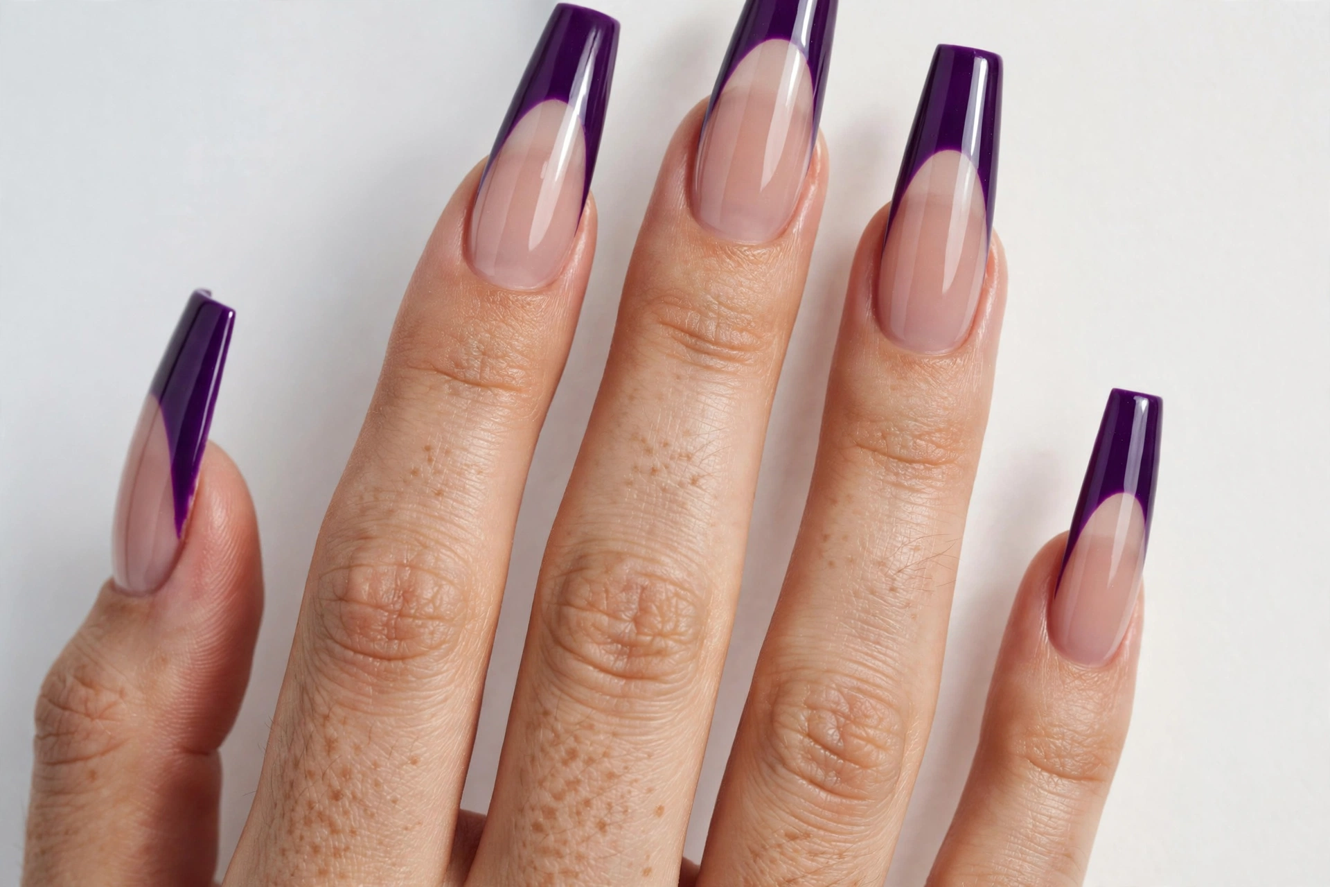 Coffin French tip nails with rich purple glossy tips on a sheer nude base, shown on long coffin nails.
