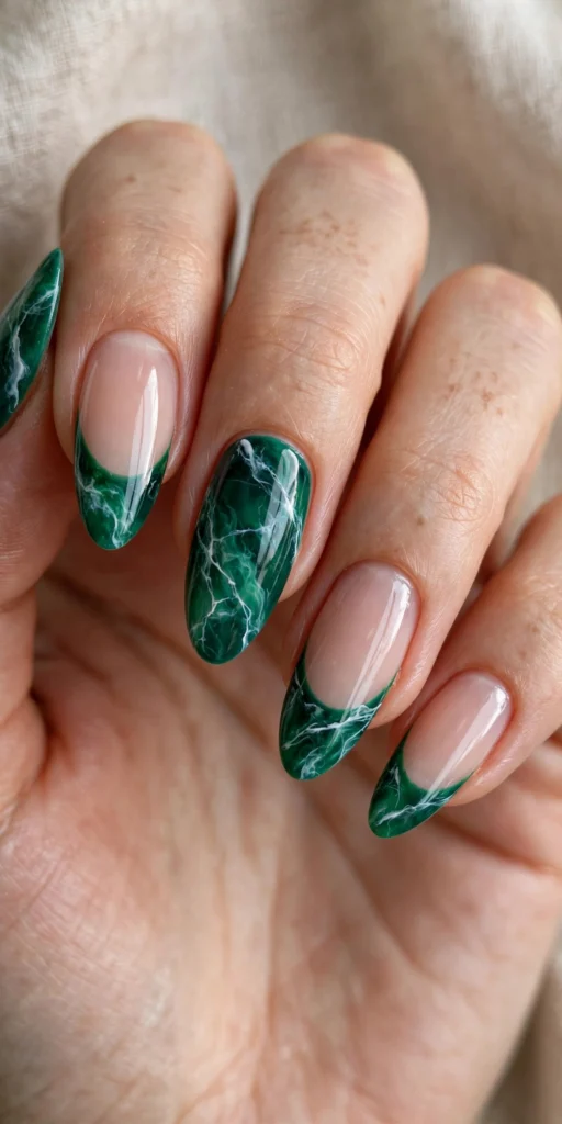 Almond nails with emerald green marble-effect French tips with white veining and one full marble accent nail.