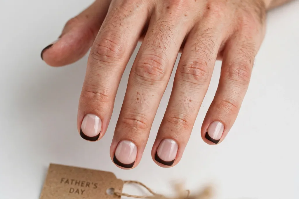 Father's Day French tip nails with deep espresso brown matte tips on a sheer natural base, shown on a man's hands with short squoval nails.