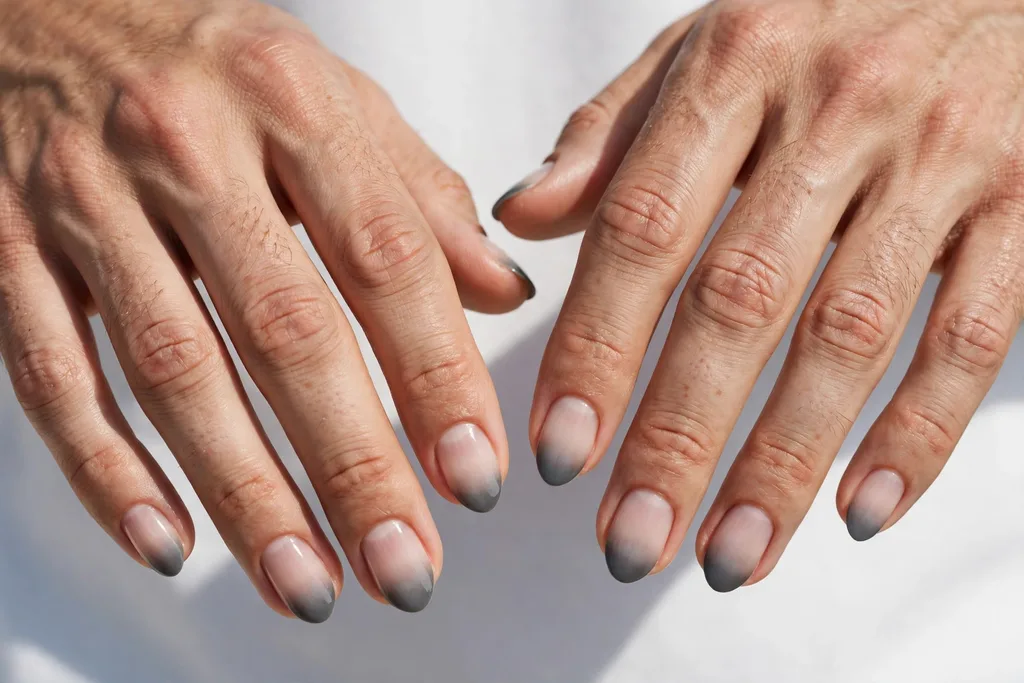 Father's Day French tip nails with graphite grey tips fading softly into a clear base, shown on a man's hands with short almond-shaped nails kept short and neat.