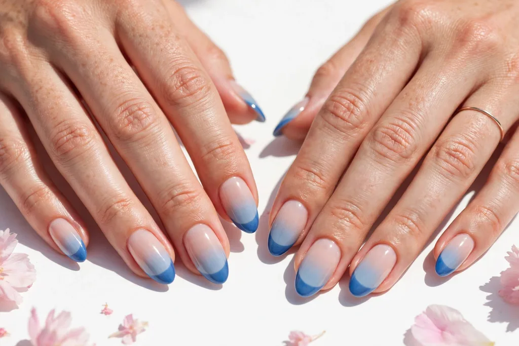 Fourth of July weekend French tip nails with a pale blue ombre fade from deeper blue tips into a sheer nude base, shown on medium almond nails.