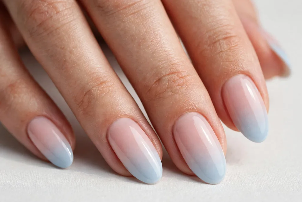 Memorial Day French ombre nails with tips fading from pale blue into a soft pink base, shown on medium almond nails.
