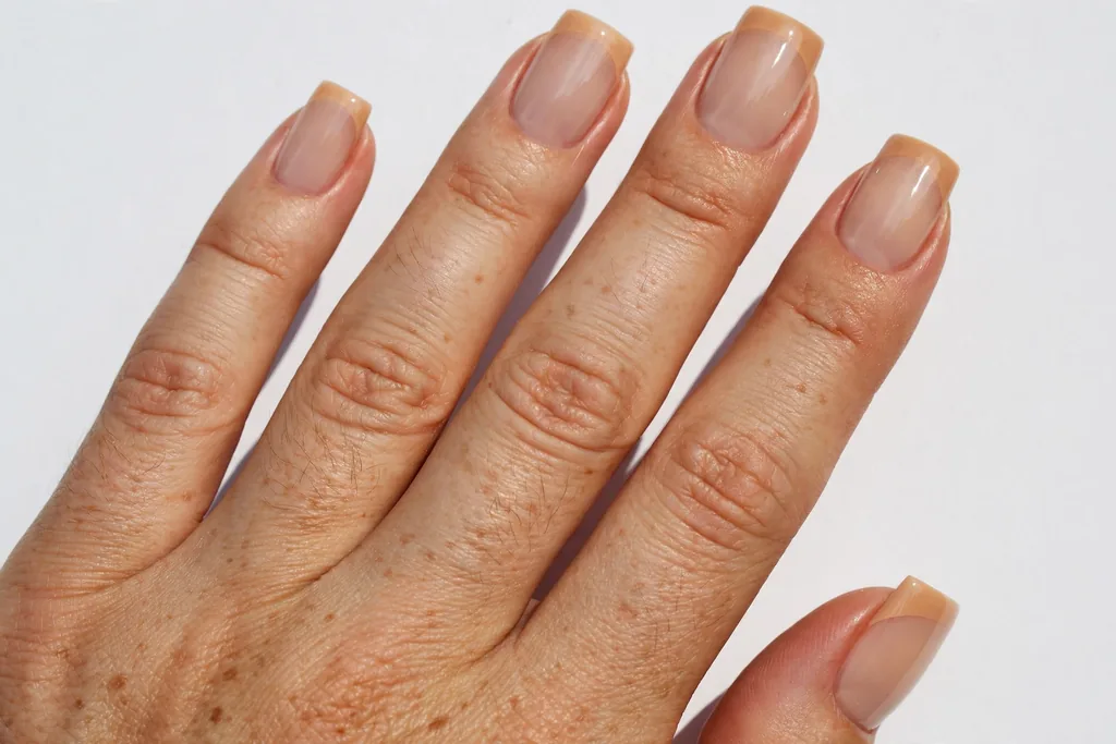 New Year's Day French tip nails with warm nude tips on a sheer nude base and a high-gloss finish, shown on medium square nails.