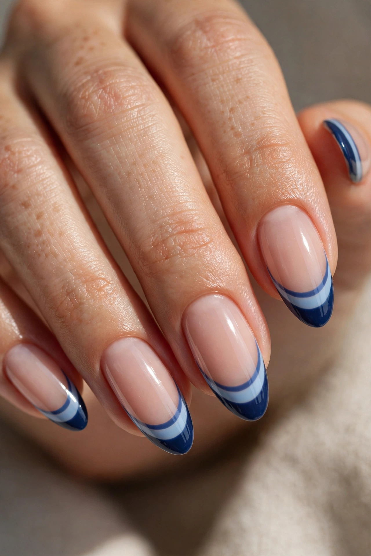 Almond nails with two-tone French tips pairing a lighter sky blue band beneath a deep navy band.
