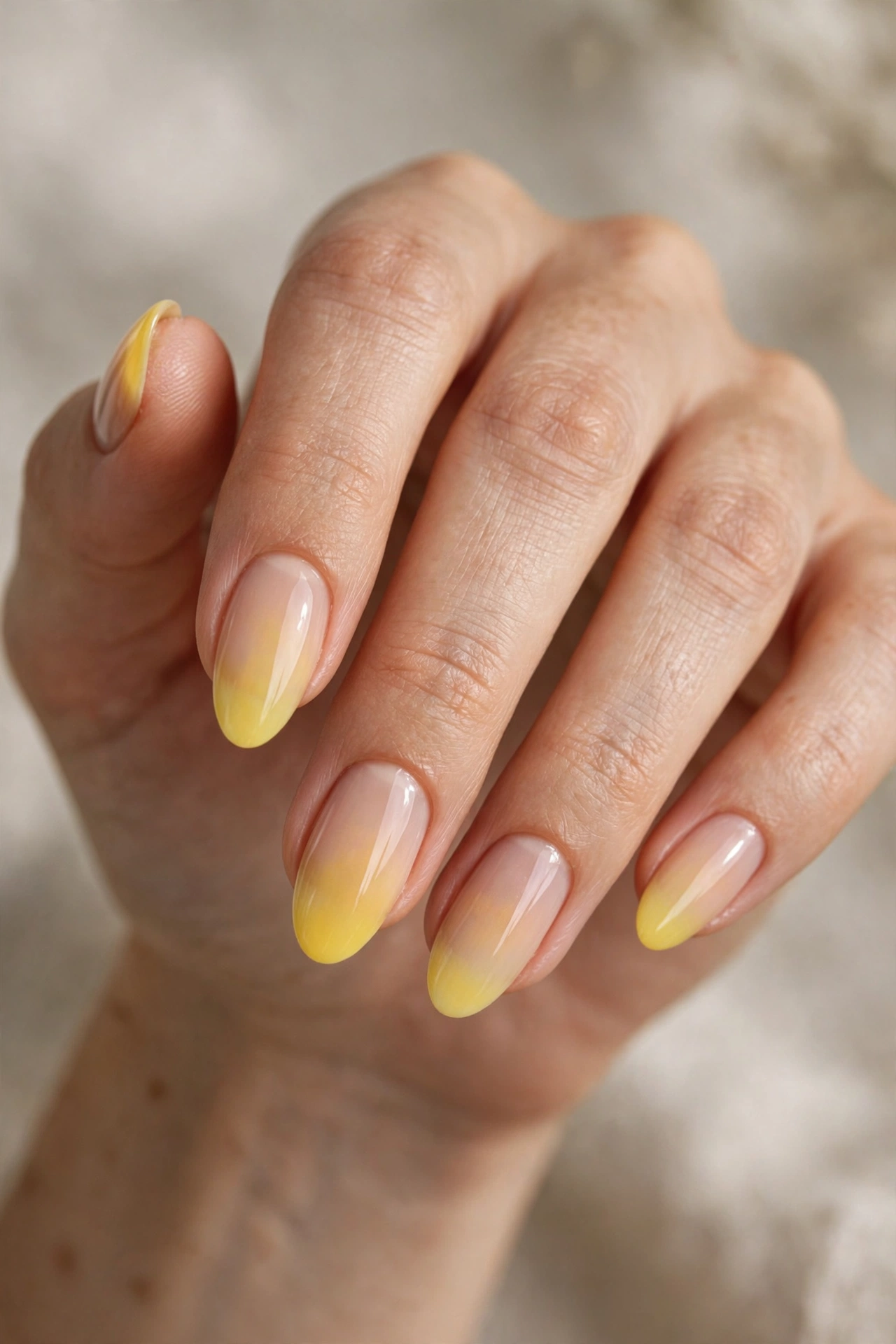 Almond nails with a soft ombre fade from sheer nude into sunny yellow at the tips.
